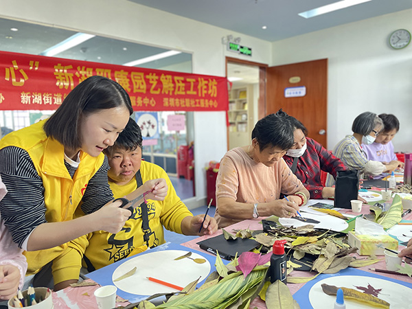 社工指导参与者制作树叶粘贴画