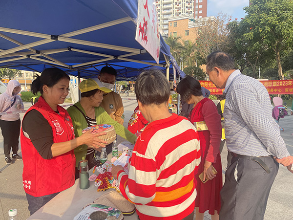 残疾人手工骨干向居民介绍残疾人制作的手工艺品